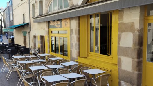 Terrasse de café chaleureuse à Nantes avec mobilier coloré et ambiance urbaine.