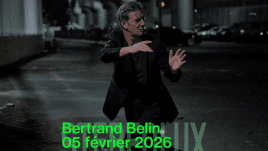 Man in black suit performing a dance move outdoors at night in Nantes, France.