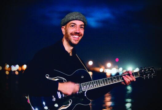 Musicien jouant de la guitare à Nantes, ambiance nocturne, vie culturelle dynamique.