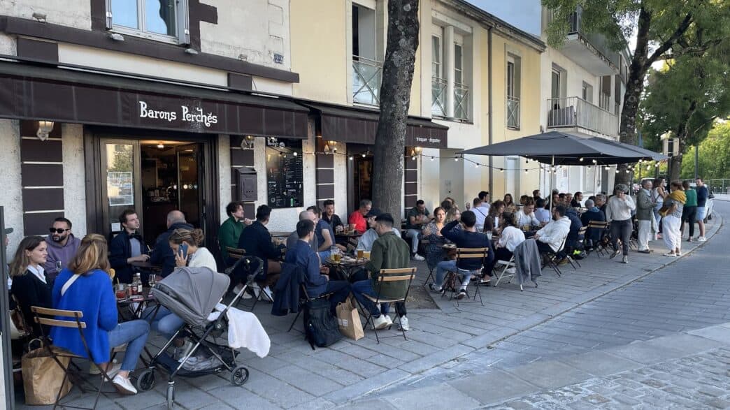 Fauteuils et tables extérieures du bar à Nantes, ambiance conviviale et touristique.