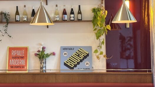 Intérieur d'un restaurant contemporain avec étagères à bouteilles, éclairage suspendu et mobilier él.