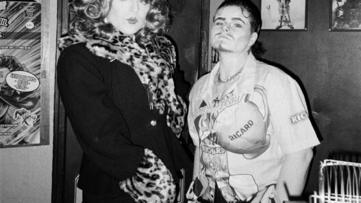 Photo de deux femmes dans un bar, ambiance rétro, costumes élégants et décontractés.