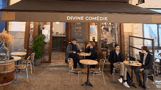 Terrasse extérieure du café Divine Comédie à Nantes avec clients assis et ambiance chaleureuse.